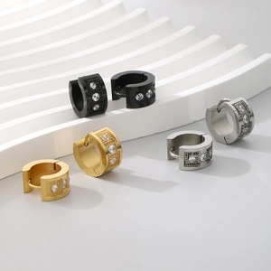 Detail of C-shaped titanium steel earrings with geometric textures and zircon inlays