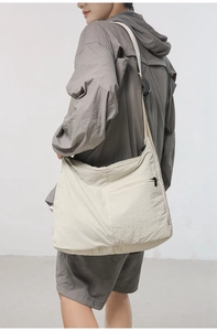 Side view of a large cream nylon crossbody bag showing drape and storage capacity