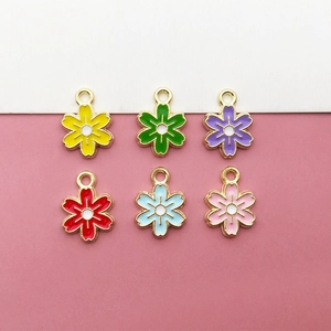 Flat lay of six colorful enamel daisy charms with gold metal edges for DIY jewelry making