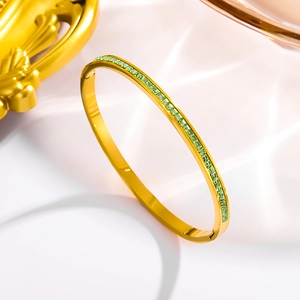 Detail of 18k gold plated stainless steel cuff bracelet with square green zircons