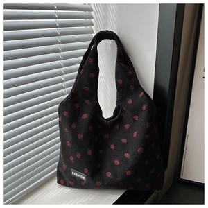 Detail of strawberry print on black corduroy tote bag with soft natural shadows