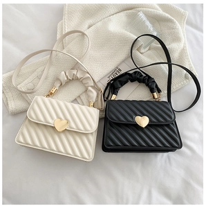 Detailed view of heart-shaped gold buckles on quilted crossbody bags with ruched handles