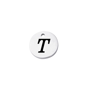 Macro shot of polished silver stainless steel round charm with engraved letter T detail
