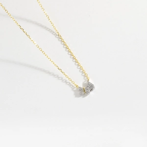 Close-up of a delicate gold chain necklace with a sparkling pavé diamond dog-shaped pendant