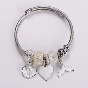 Detailed shot of silver charm bracelet with mermaid tail, shell, and heart pendants