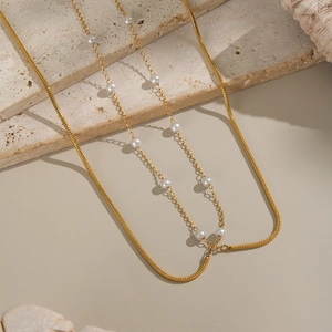 Detail of double-layer 18K gold plated necklace with delicate white pearls on a stone base