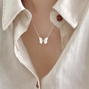 Macro detail of silver butterfly pendant necklace with intricate wing texture