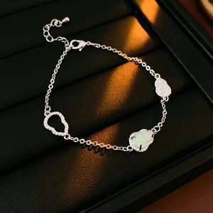 Macro shot of silver bracelet featuring hollow and gemstone-inlaid gourd charms