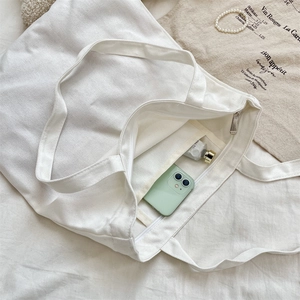 Internal view of white canvas tote bag showing smartphone and lotion storage space
