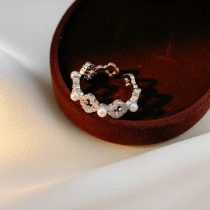 Détail d'une bague perle plaquée or 18k avec coeurs et zircons sur un écrin en velours