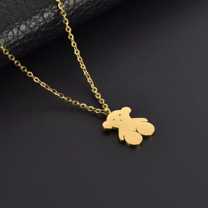 Macro shot of gold stainless steel bear pendant necklace on black leather texture