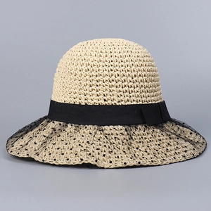 Close-up of beige woven sun hat featuring delicate black polka dot tulle and lace bow