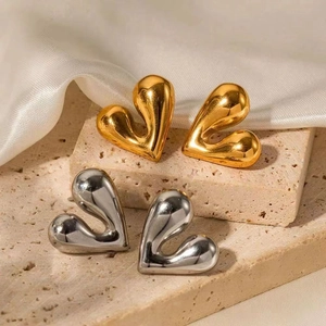 3D heart earrings in polished gold and silver finish on a luxury stone stand
