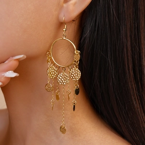 Gros plan de boucles d'oreilles bohèmes dorées avec disques martelés sur un mannequin