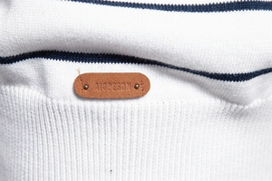 Close-up of striped knit sweater texture with brown leather embossed logo patch