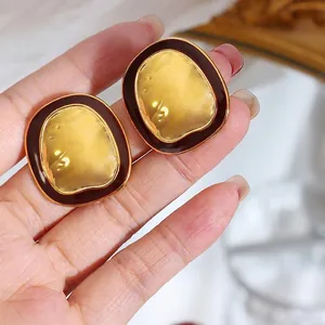 Vintage oversized gold-tone earrings with textured hammer finish and dark red border