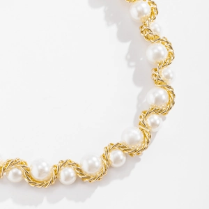 Detailed close-up of golden twisted chain and white round pearls on the elegant necklace