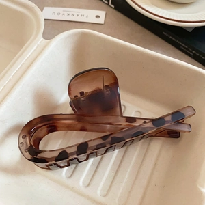Macro shot of amber leopard print hair claw clip in a minimalist tray setting
