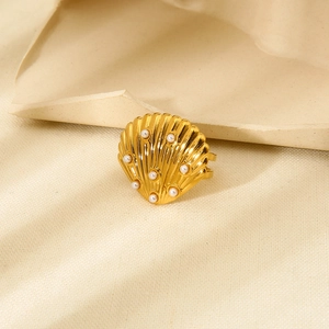 Close-up of a 18K gold plated shell ring with pearls on a beige textured fabric