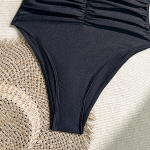 Detail view of black one-piece swimsuit featuring side shirring and premium matte fabric