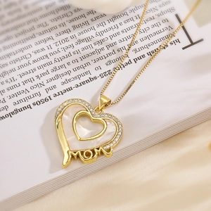 Gold heart MOM pendant necklace with shell inlay and cubic zirconia on a book