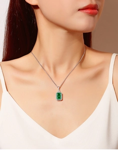 Close-up of S925 silver necklace with emerald-cut green gemstone and halo diamonds