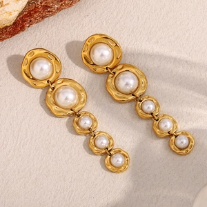 Gros plan de boucles d'oreilles dorées avec cinq perles blanches de tailles graduées
