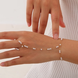 Detail of layered gold snake chain hand chain with elegant white pearls on model's hand