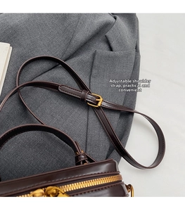 Detail of adjustable leather strap with gold buckle on dark brown crossbody box bag