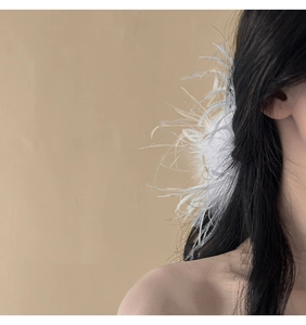 Close-up of fluffy white ostrich feather hair claw clip on model's head for hair styling