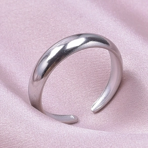 Close-up of polished silver stainless steel adjustable ring on pink silk background