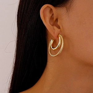 Detail of gold double-layered C-shaped hoop earrings with textured outer layer on model