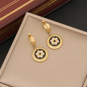 Detail view of gold earrings with black flower design and pearls on a vintage jewelry box