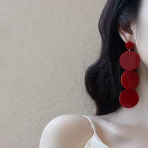 Macro shot of minimalist red multi-layered acrylic round tassel drop earrings on model
