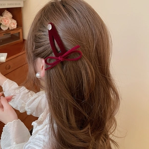 Detail of dark burgundy velvet bow hair clip worn by a model in a retro style