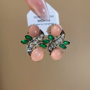 Detail of vintage gold-toned earrings with pink opal stones and green marquise crystals
