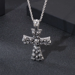 Detailed view of silver gothic cross pendant featuring stacked 3D skull reliefs and twist chain