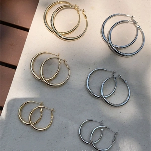 Detailed close-up of chunky gold and silver hoop earrings in various sizes on fabric