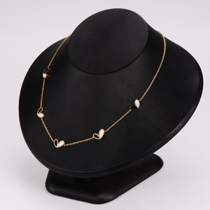Golden heart necklace with black and white enamel pendants on a black jewelry bust