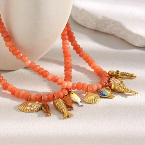 Close-up of orange beaded necklace with 18K gold plated shell and octopus sea life charms