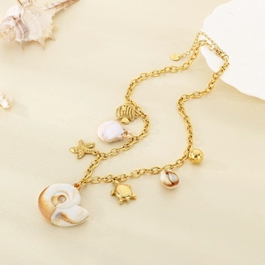 Gold stainless steel ocean necklace with shell and starfish charms on a beach background