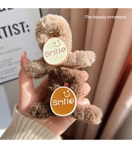 Detailed view of plush hair clips in light and dark brown with a white smile emoji design