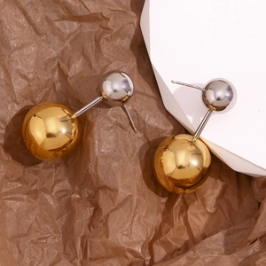 Makroaufnahme der zweifarbigen Ohrringe mit Gold- und Silberkugeln auf Packpapier