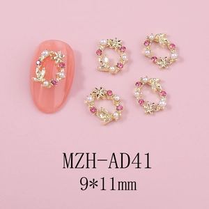Détail macro du charm nail art couronne dorée avec strass roses et perles blanches