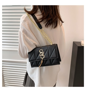 Close-up of black quilted shoulder bag with gold double-S logo and tassel detail