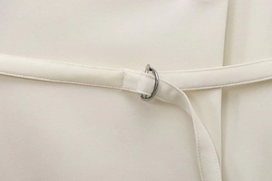 Detail of beige blazer fabric belt with a metallic D-ring buckle closure system