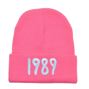 Detailed view of the bright pink knit beanie featuring white 1989 number embroidery