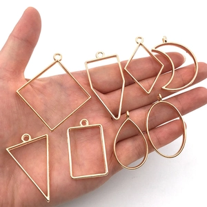 Eight gold geometric hollow alloy frames for DIY jewelry resin making shown in hand