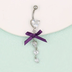 Détail d'un piercing de nombril avec nœud violet et pendentifs en zircone en forme de cœur