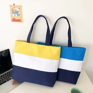 Close-up of three-color patchwork canvas tote bags with reinforced handles on a desk